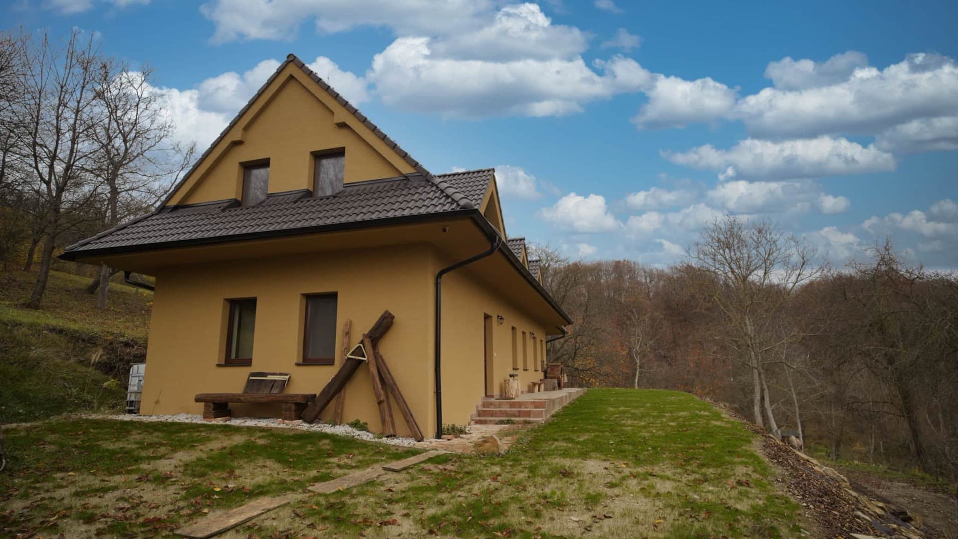 Chalupa Hochovec od záhrady, žltá fasáda pod modrou oblohou