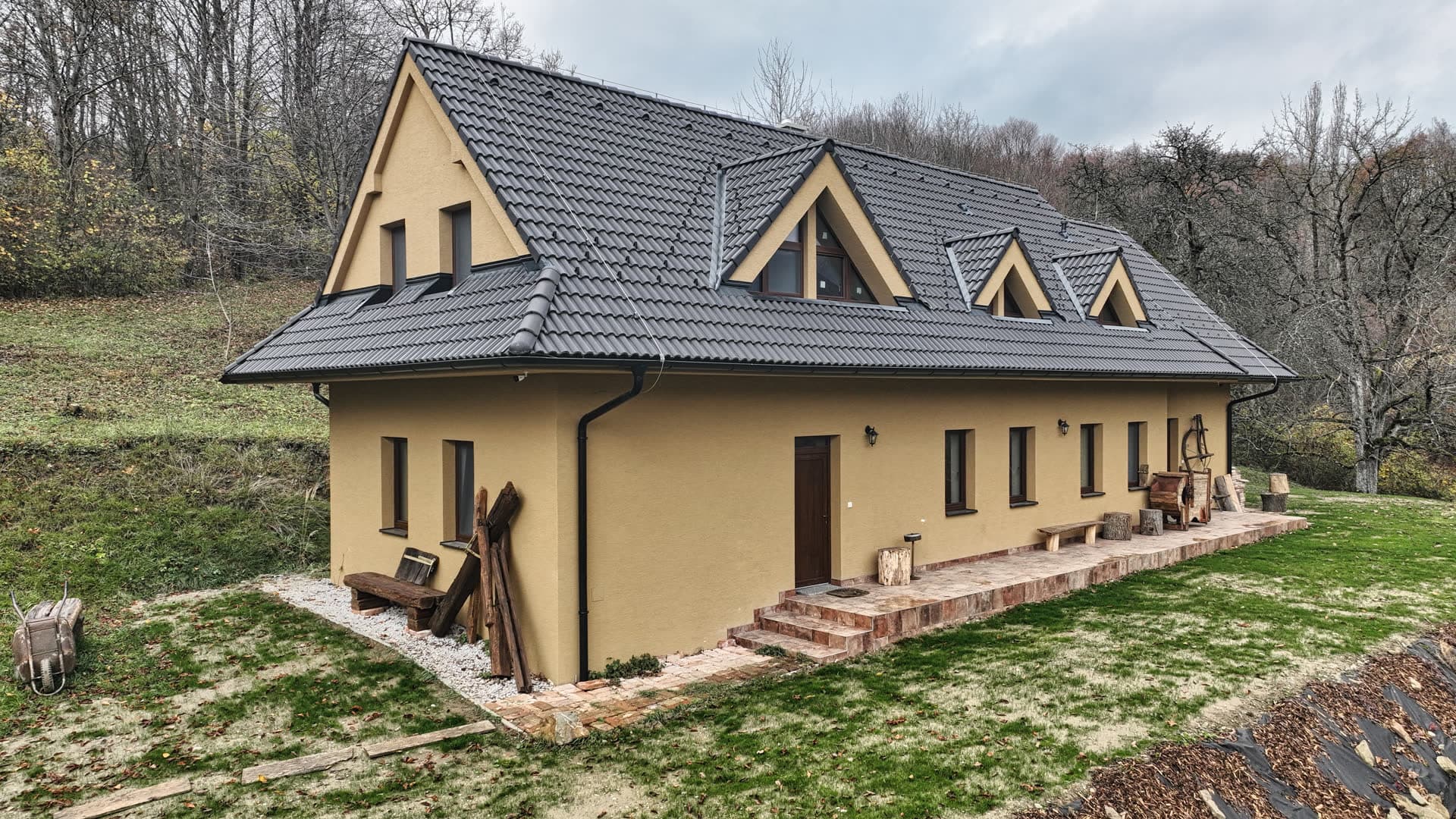 Chalupa Hochovec so žltou fasádou a tmavou strechou z výšky, obklopená jesennými lesmi
